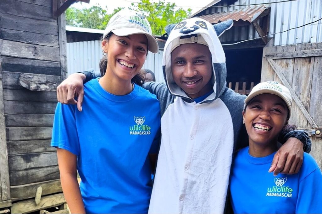 Three young people are posing for the camera with big smiles.